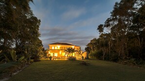 A two-story house with a well-maintained lawn and surrounding trees. - Hacienda B-03 (Punta Cana)