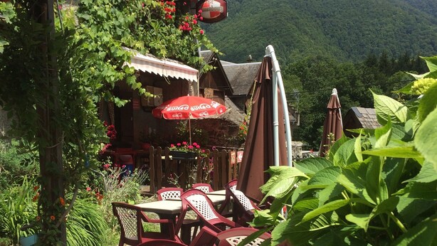 An outdoor seating area with tables and chairs, surrounded by potted plants and flowers. - Auberge des Pyrénées (Campan)