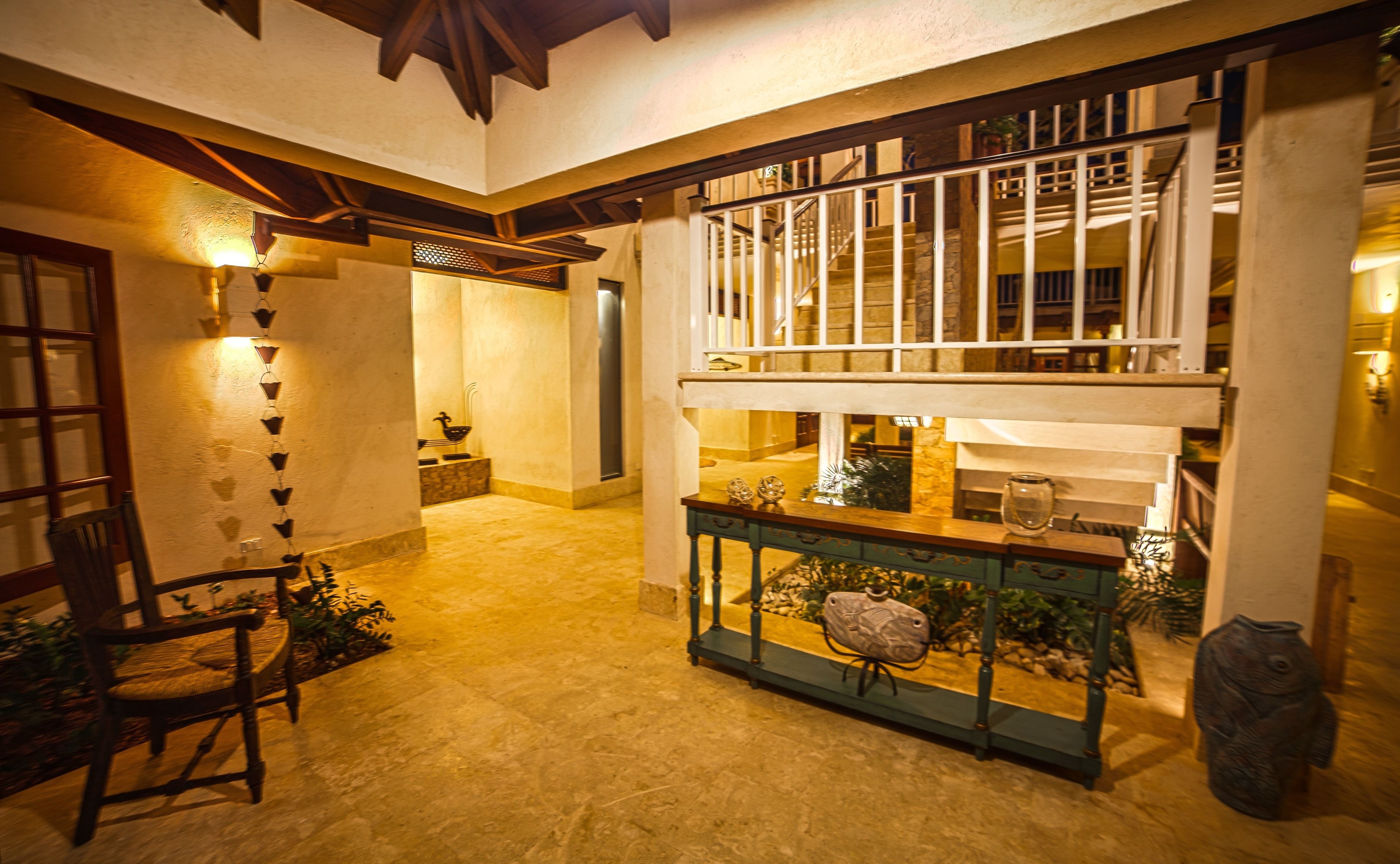 A spacious foyer with a staircase, a wooden chair, and a console table with decorative items.