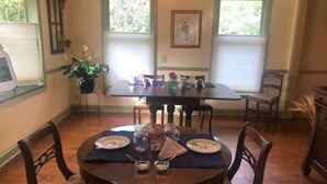A dining area with a round table set for four, surrounded by wooden chairs. - Miller-Dunham House Bed & Breakfast (Odessa)