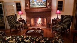 A cozy living room with a fireplace, striped armchairs, and a floral sofa. - Miller-Dunham House Bed & Breakfast (Odessa)