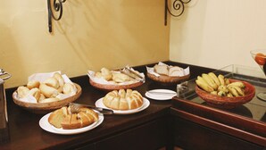 A buffet table with various baked goods and fruits.