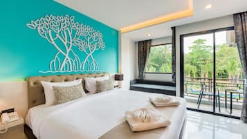 A modern hotel room with a large bed, a view of a swimming pool, and a tropical landscape visible through the window.
