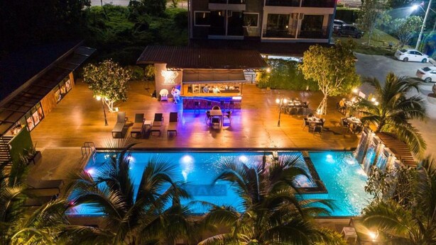 Uma área de piscina no terraço com espreguiçadeiras, bar e piscina.