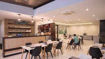 A modern restaurant with a bar area, tables, and chairs.