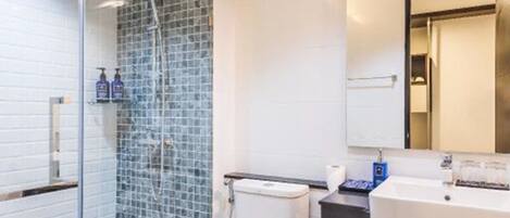Une salle de bain moderne avec une douche Ă parois de verre, des toilettes blanches et un meuble-lavabo avec un miroir.