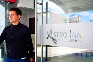 Un hombre de pie frente a un cartel del Hotel Astro Inn Express.
