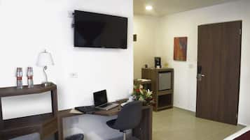 Habitación de hotel con escritorio, silla, televisor y puerta.
