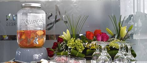 A kitchen counter with a fruit punch, flowers, and glassware.
