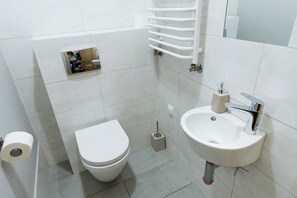 Een badkamer met toilet, wastafel en handdoekhouder.