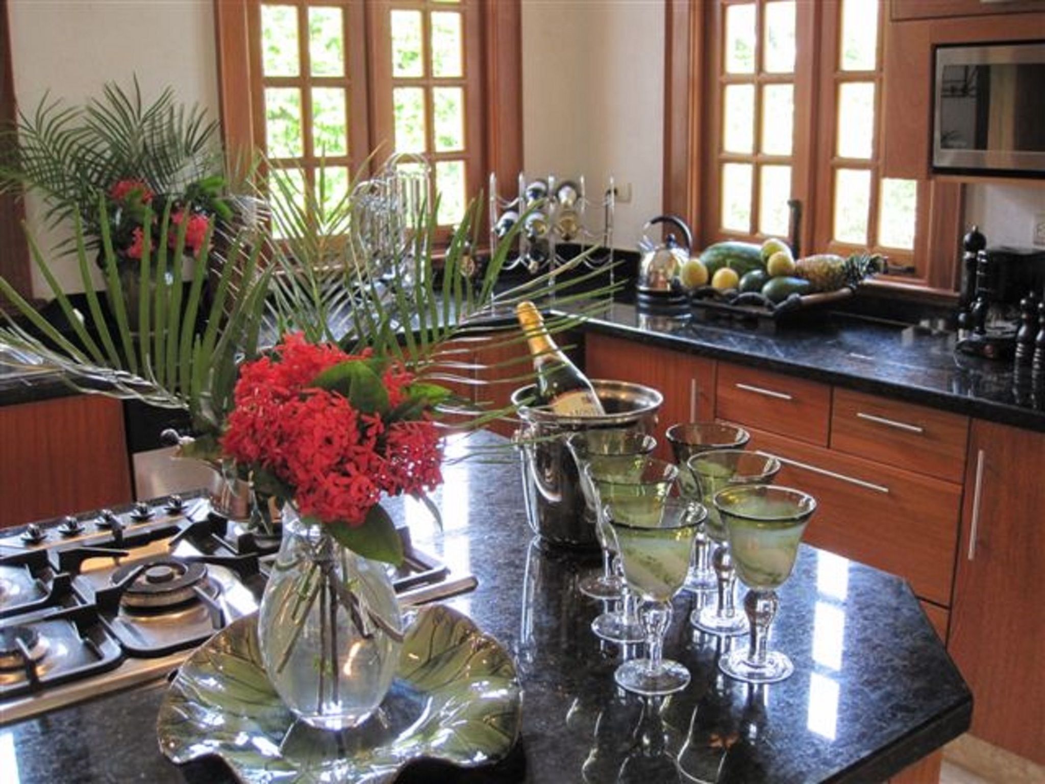 A kitchen with a marble countertop, a gas stove, a sink, and various kitchen utensils.