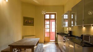 A kitchen with wooden flooring, a wooden table, and cabinets. - Krakowrentals - Stanislas Apartment (Kraków)