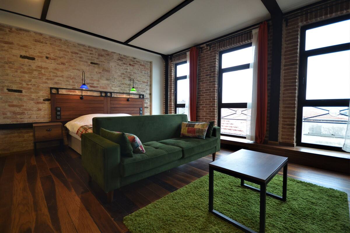 A modern living room with a green sofa, a wooden coffee table, and a brick wall.