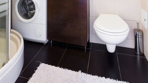 Une petite salle de bain équipée d’un lave-linge, de toilettes, d’un lavabo et d’un miroir.