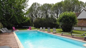 A rectangular swimming pool with a wooden deck and lounge chairs. - Au Cocon de Sologne (Soings-en-Sologne)