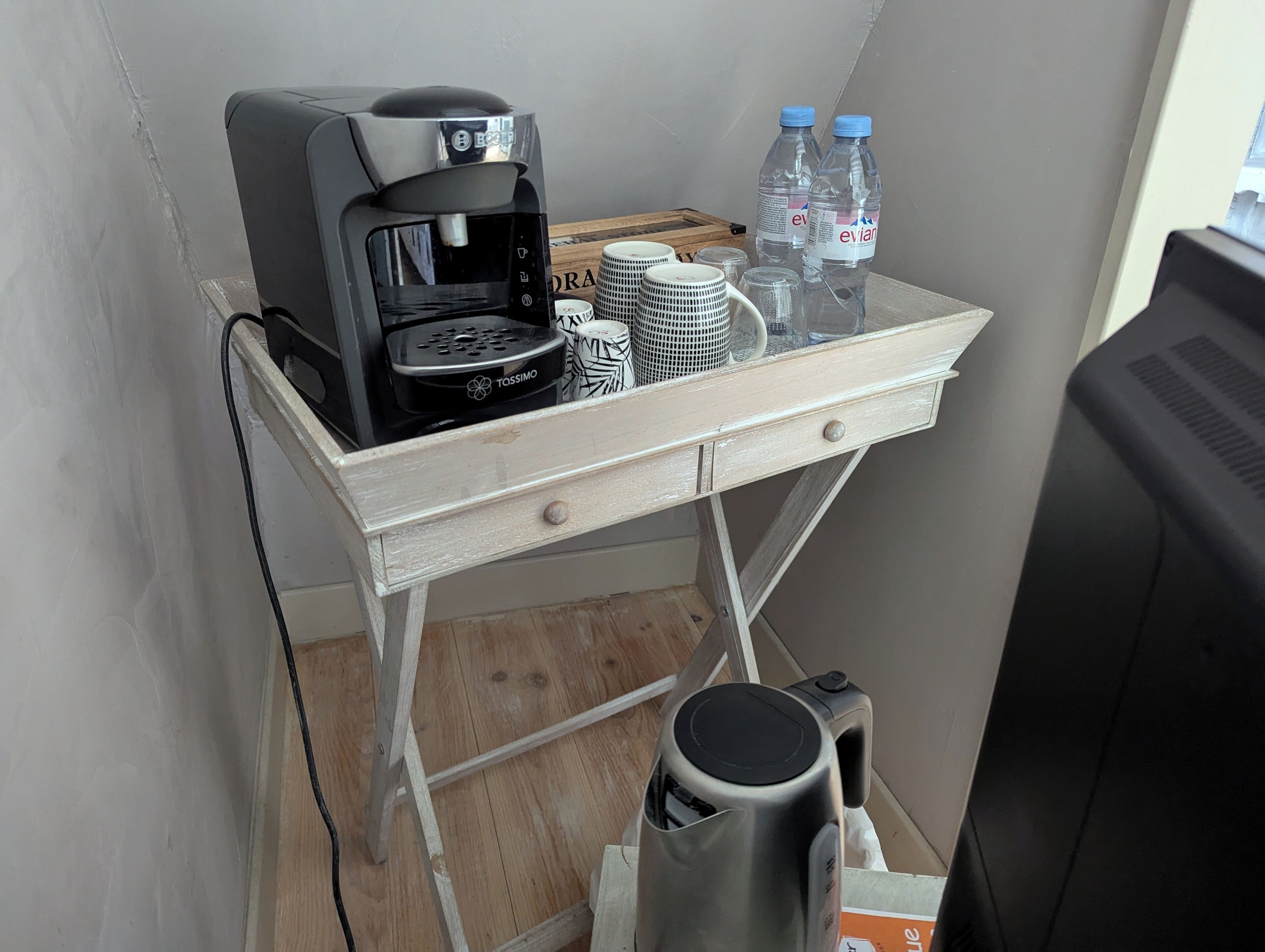 A kitchenette with a coffee maker, water bottles, and a trash bin.