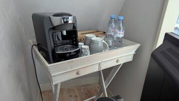 Une petite cuisine équipée d’une machine à café, de bouteilles d’eau et d’une poubelle.