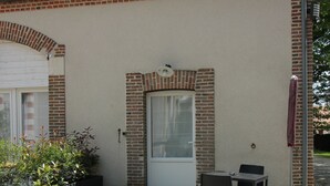 A small building with a tiled roof, a brick facade, and a door. There is a small table and two chairs outside. - Au Cocon de Sologne (Soings-en-Sologne)