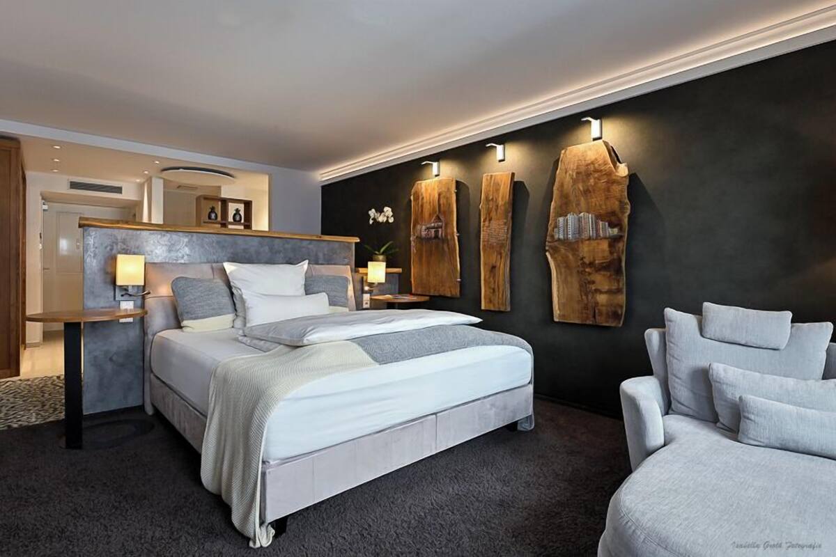 A modern bedroom with a large bed, bedside tables, a desk, and a chair.