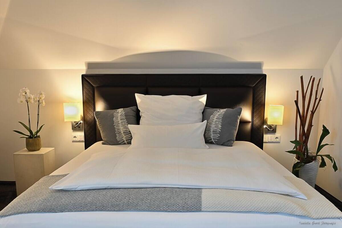A hotel room with a large bed, two bedside tables, and a nightstand.