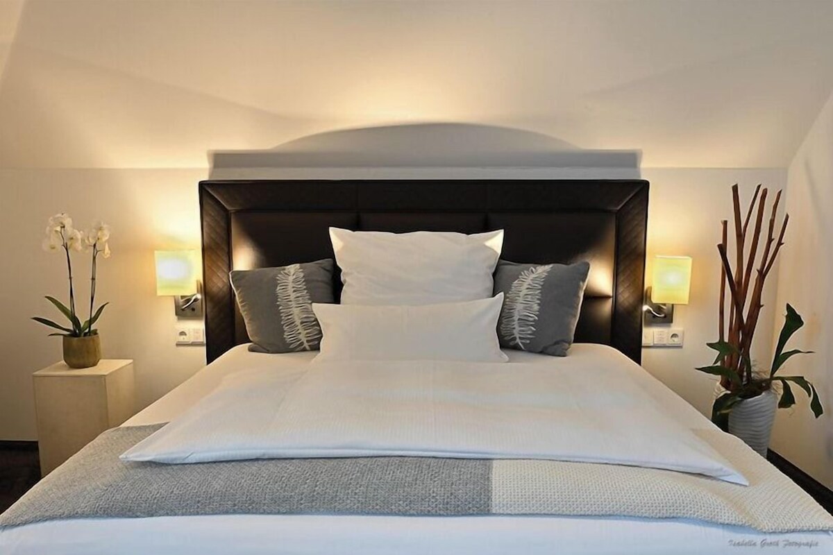 Une chambre d’hôtel avec un grand lit, deux tables de chevet et une petite table d’appoint.