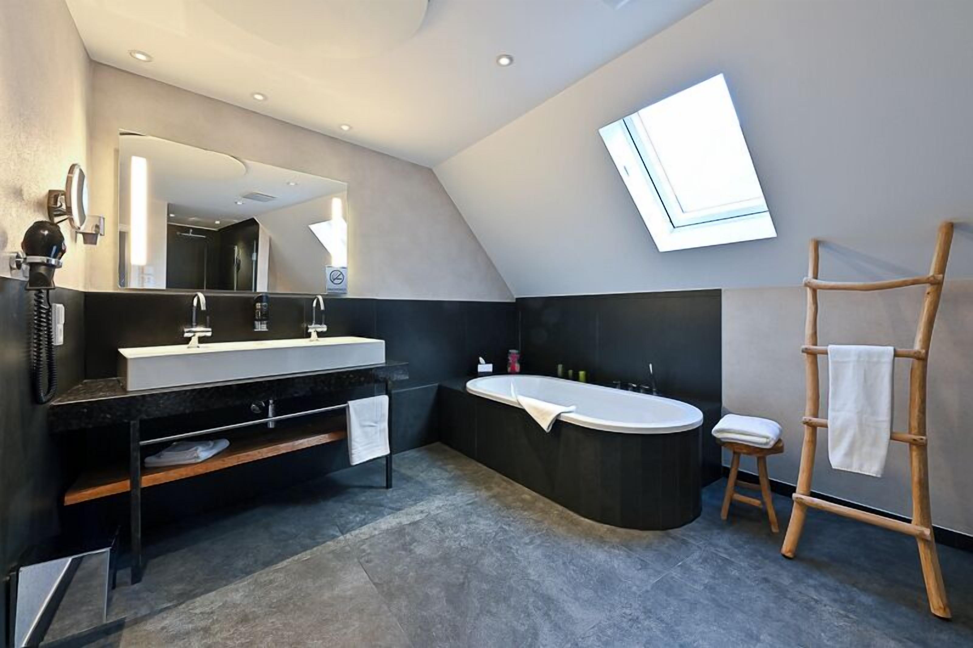 Une salle de bain moderne avec un grand miroir, une baignoire sur pieds et un porte-serviettes en bois.