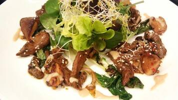 A plate of stir-fried beef with vegetables and sprouts on a white plate.
