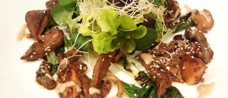 A plate of stir-fried beef with vegetables and sprouts on a white plate.