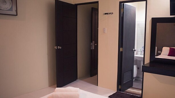 A hotel room with a bed, a bathroom visible through an open door, and a small rug on the floor. - Hotel Turista Canlubang (Calamba)
