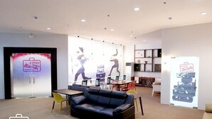 A modern hotel lobby with a blue leather sofa, yellow chairs, a dining area, and a reception desk. - Hotel Turista Canlubang (Calamba)