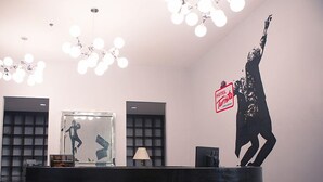 A hotel reception desk with a modern design, including a large mirror, a digital screen, and a decorative sculpture of a dancing figure. - Hotel Turista Canlubang (Calamba)