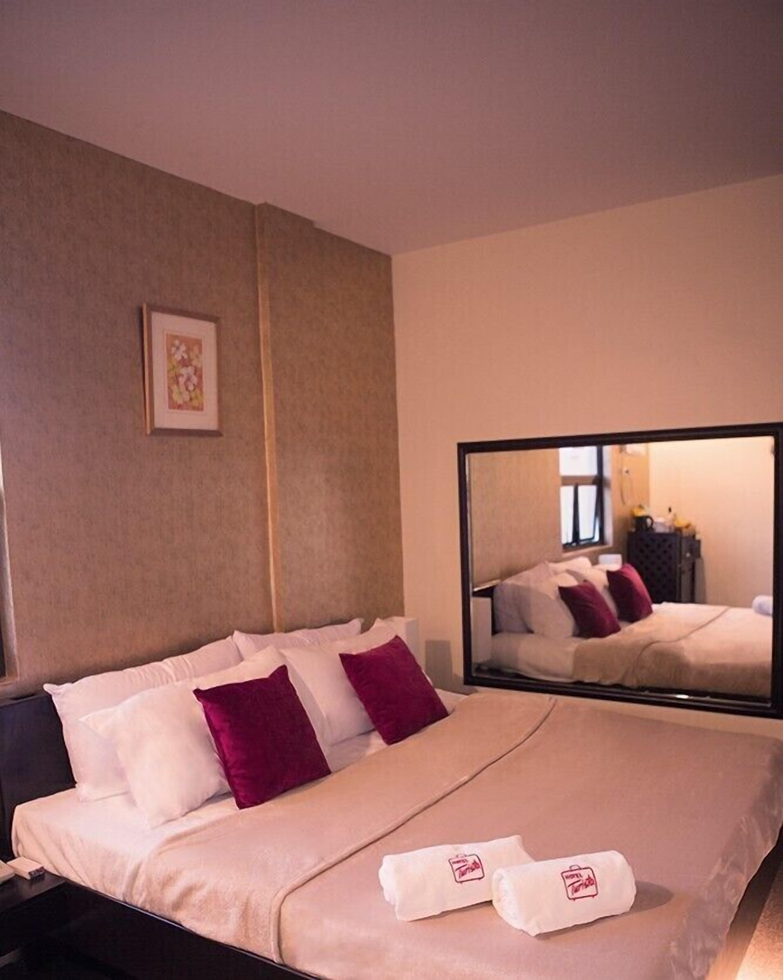 Habitación de hotel con una cama grande, un espejo y un cuadro en la pared.