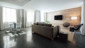 Een moderne woonkamer met een bank, een salontafel en een aan de muur bevestigde televisie.
