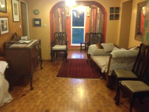 Un salón acogedor con suelo de madera, un sofá, una silla y una mesita.