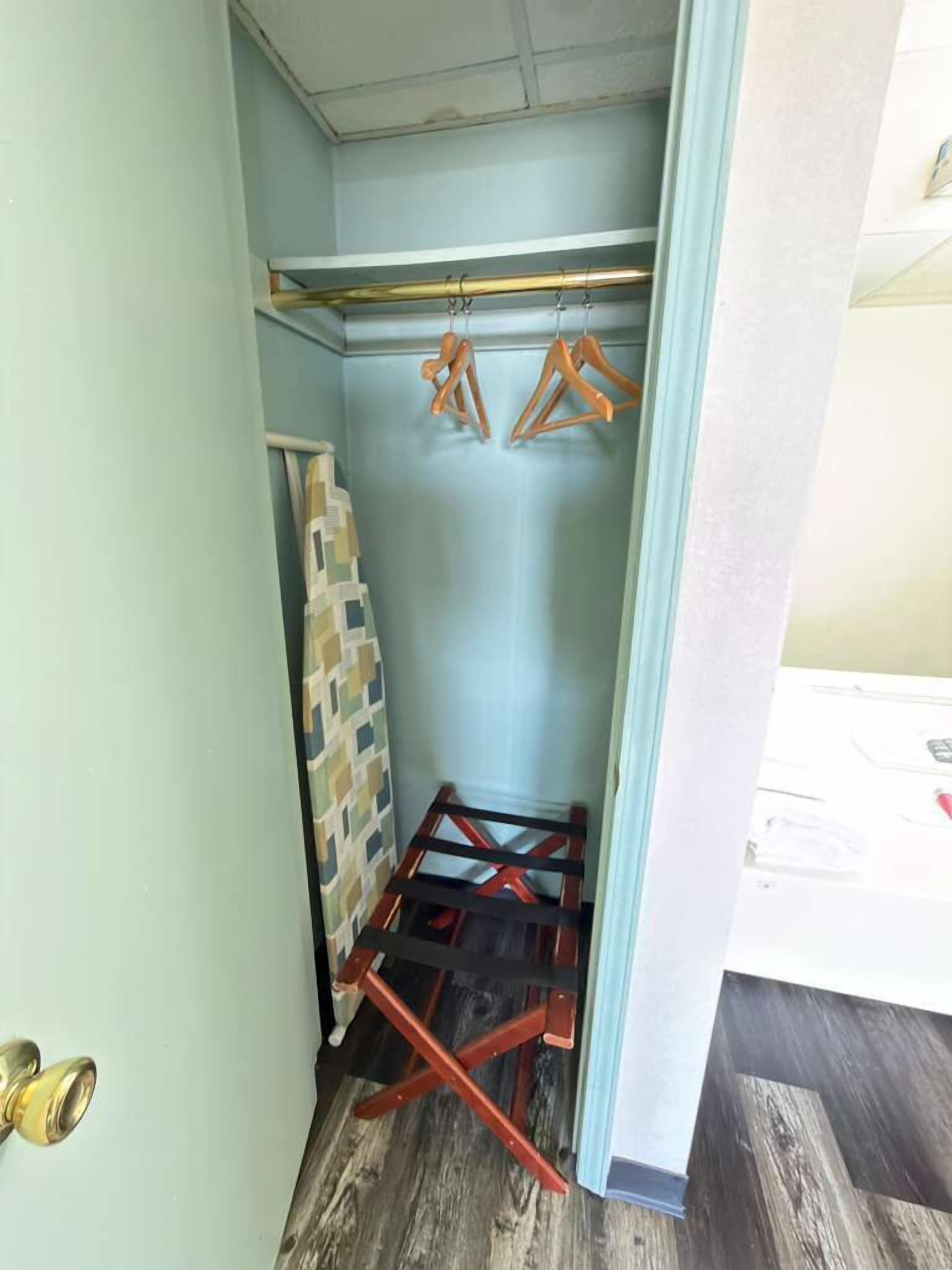 A narrow hallway with a wooden ladder, a hanging rack with clothes, and a patterned wall.