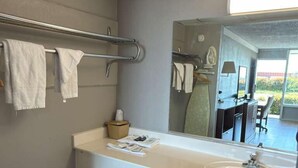 Un baño moderno con un lavamanos grande, toallero y un espejo que refleja un comedor.