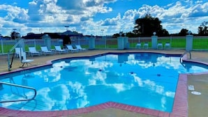 Una piscina bajo un cielo azul despejado y nubes.
