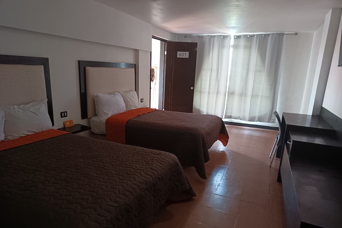 A hotel room with two beds, a desk, and a door marked with the number 601.