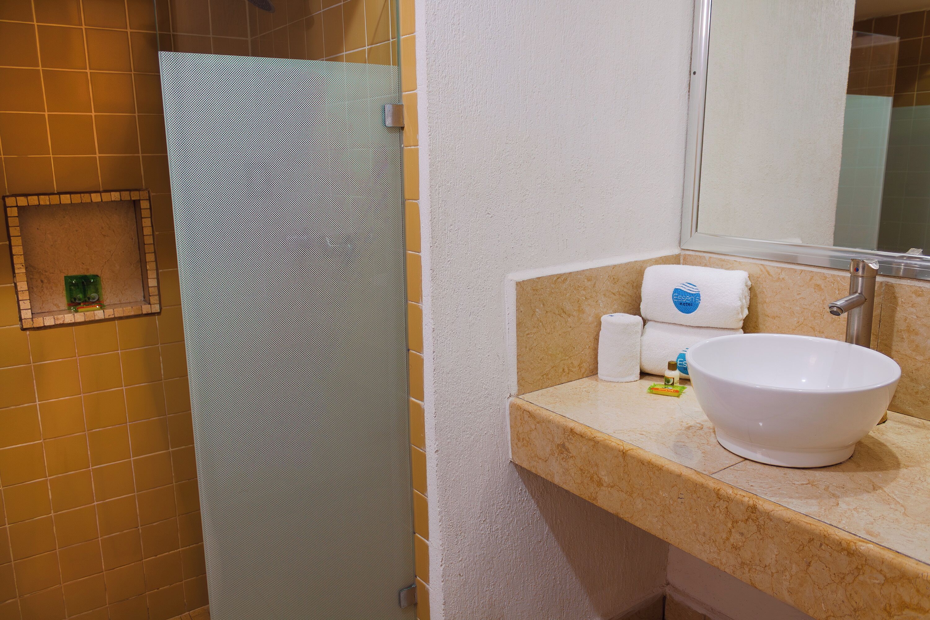 A bathroom with a beige tiled wall, a white sink with a large bowl, and a mirror above the sink.