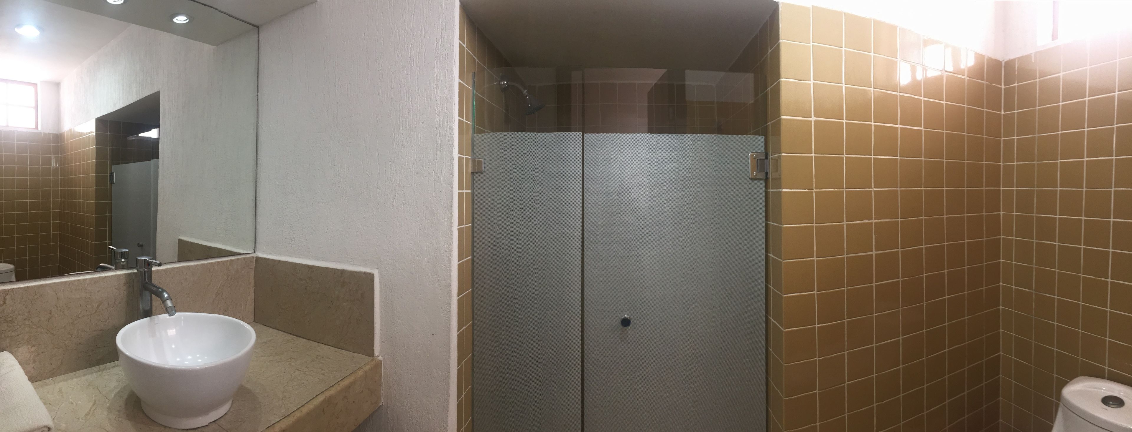 Un baño con lavamanos blanco, un espejo y un box de ducha.