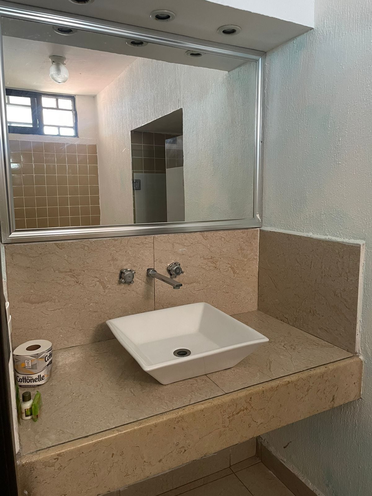 Une salle de bain avec un lavabo blanc, deux robinets et un miroir au-dessus.