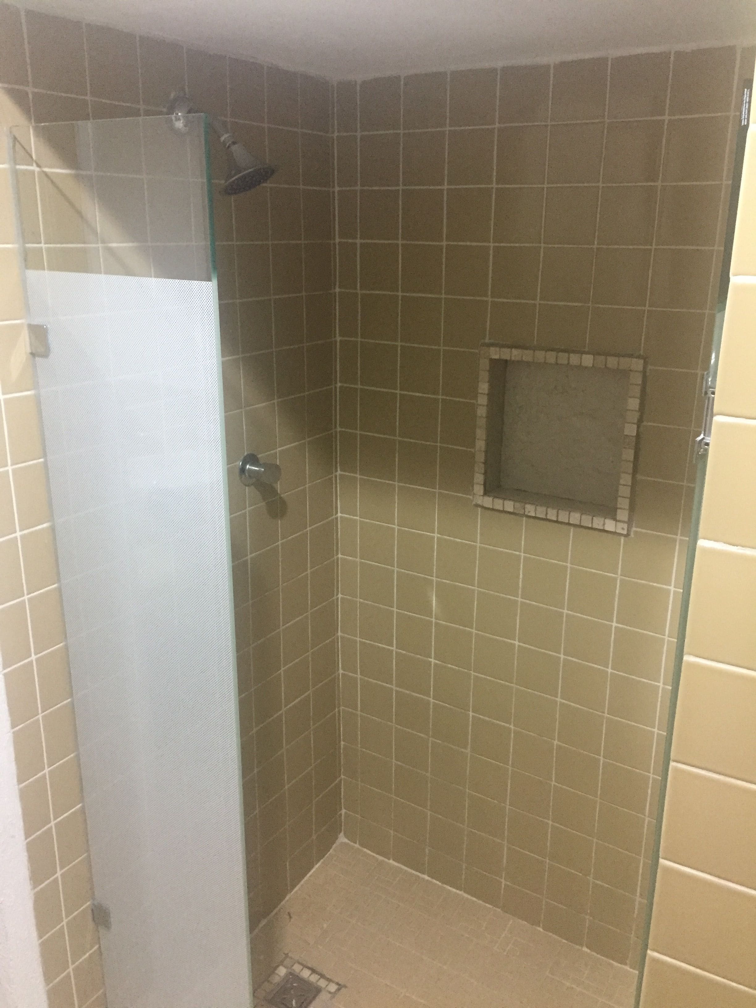 A small, enclosed shower area with tiled walls and a glass door.