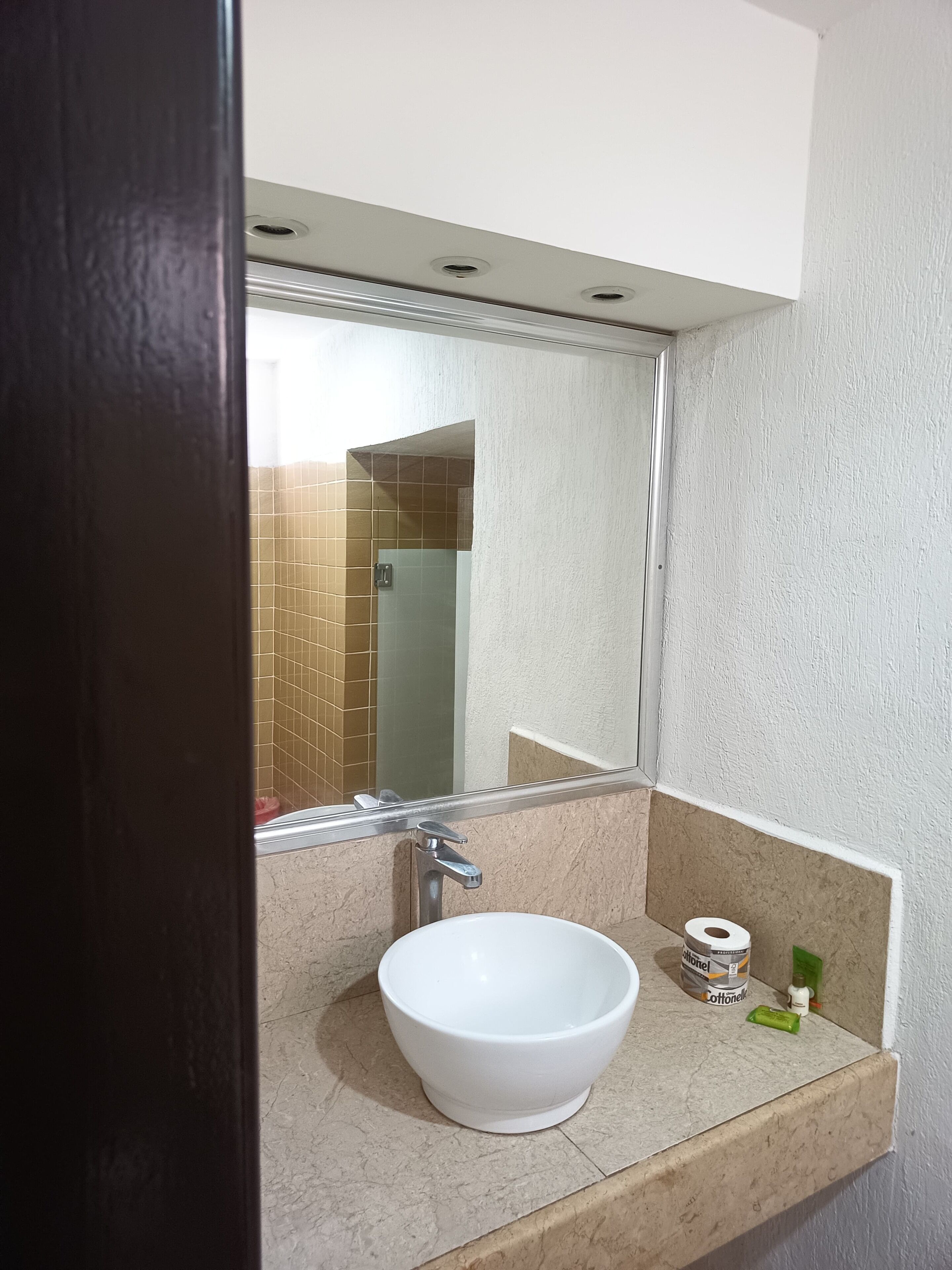 Une salle de bain avec un lavabo blanc, un miroir et un distributeur de serviettes.