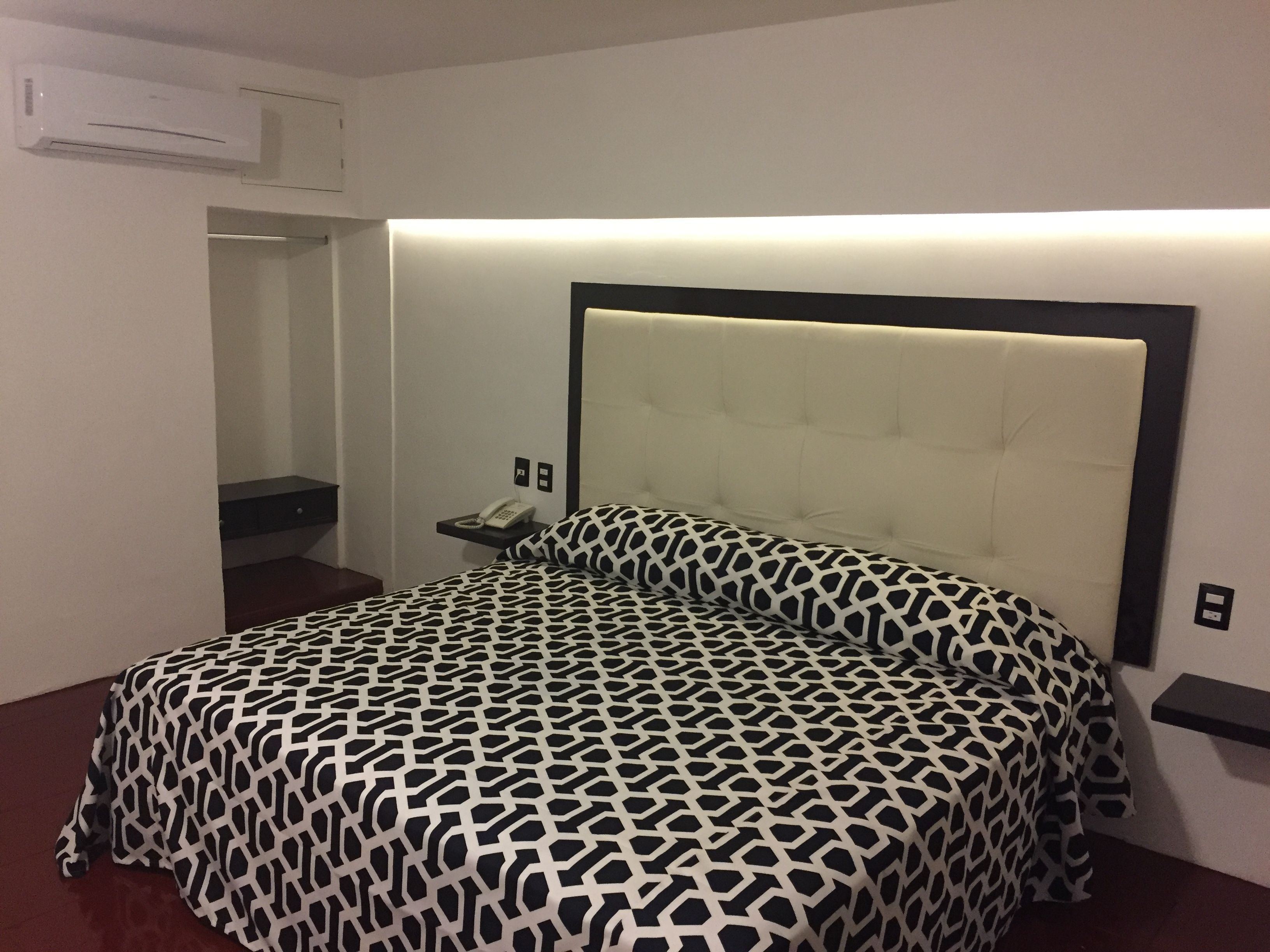 A bedroom with a bed, bedside table, and a phone.