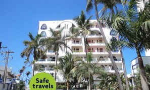 A multi-story hotel with balconies, a pool, and palm trees. - Essen's Hotel (Mazatlán)