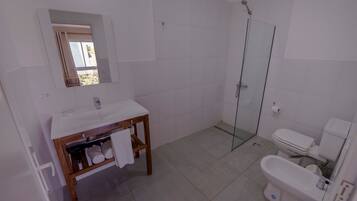 Un baño con tocador de madera, cabina de ducha de vidrio y un inodoro.