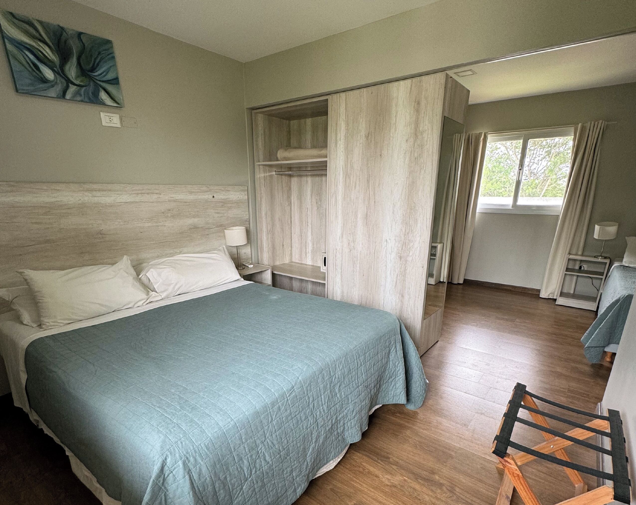 A hotel room with a bed, bedside table, and a wardrobe.