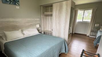 A hotel room with a bed, bedside table, and a wardrobe.
