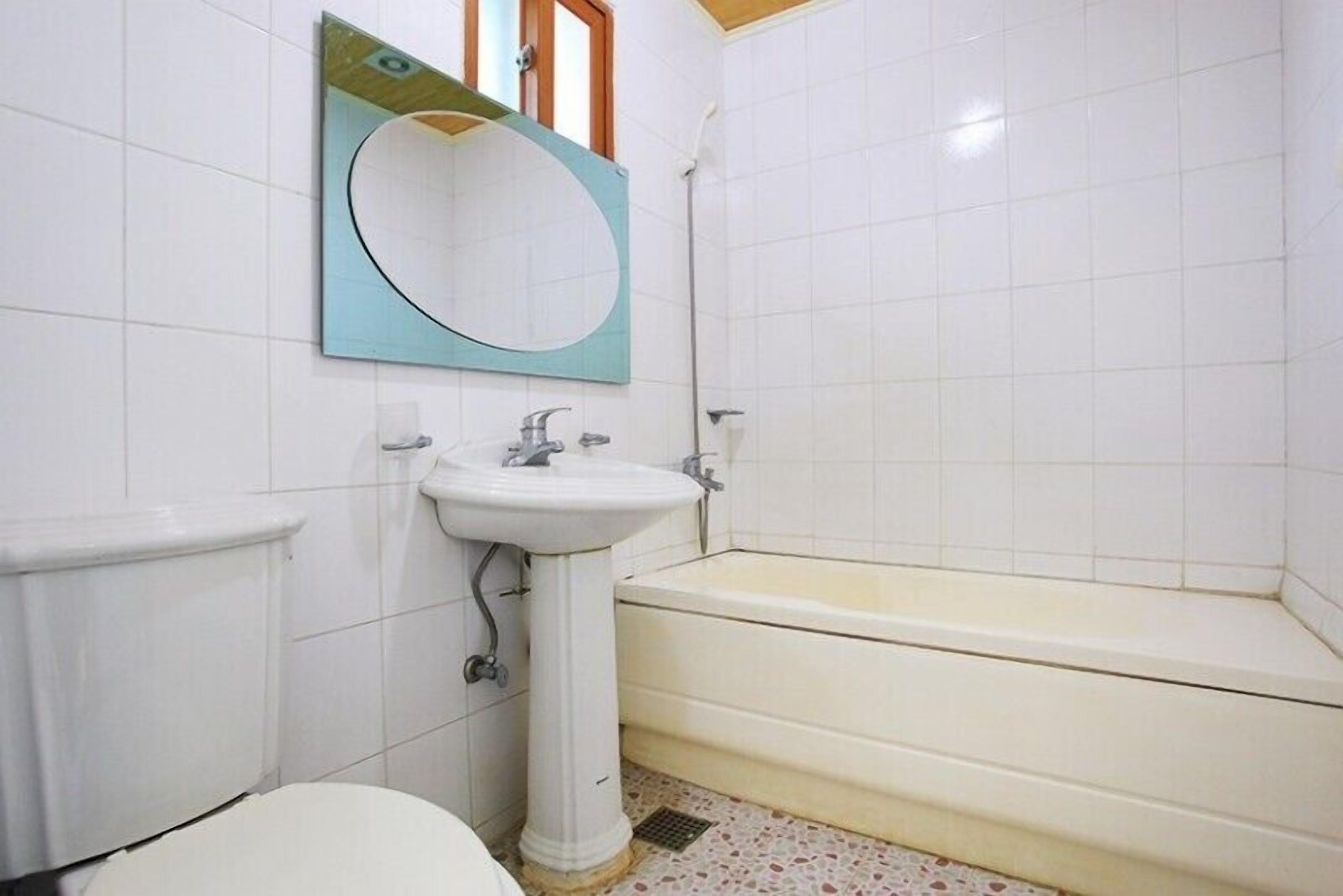 Une salle de bain comprenant des toilettes, un lavabo sur colonne et une baignoire.
