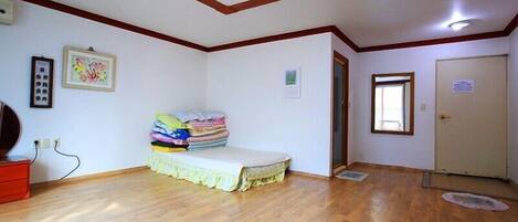 A room with a bed, a red dresser, a door, and a ceiling light.